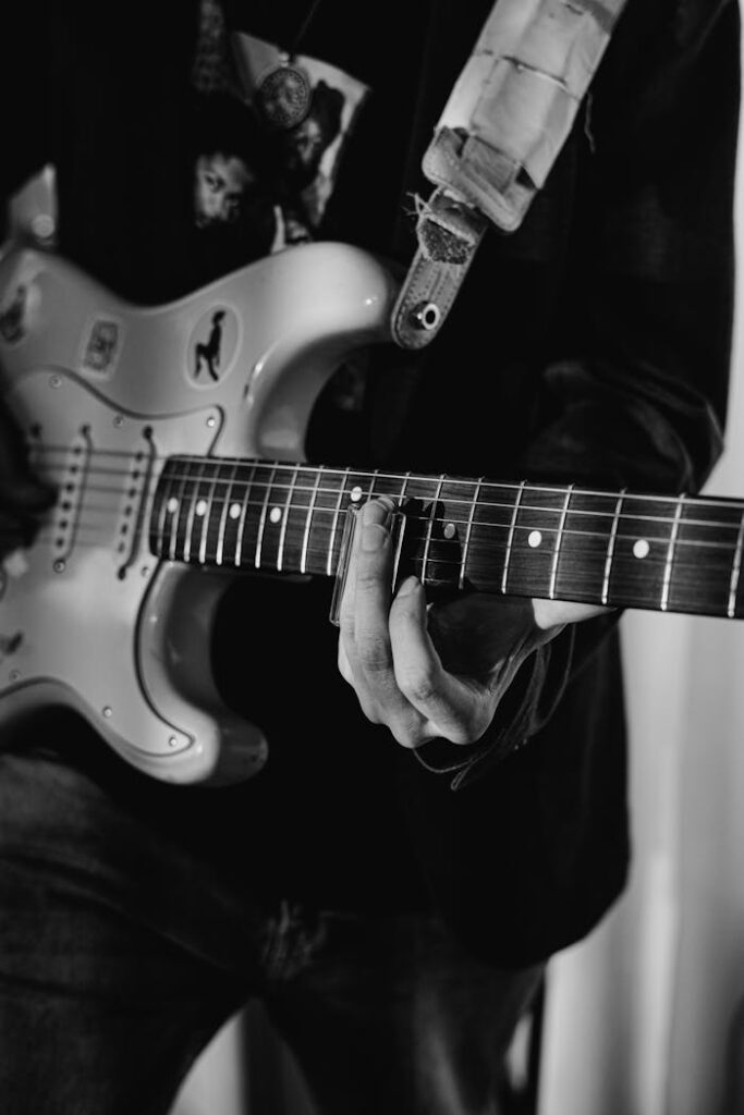 Black and white close-up of a musician playing an electric guitar.